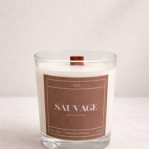 Bougie parfumée Sauvage de luxe dans son écrin noir minimaliste, notes orange ambre et mousse d'arbre.