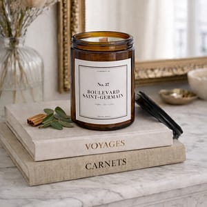 Bougie parfumée artisanale 37 Boulevard Saint-Germain, étiquette blanche sobre, posée sur un vieux livre à la reliure en cuir usée, ambiance salon de lecture ancien.